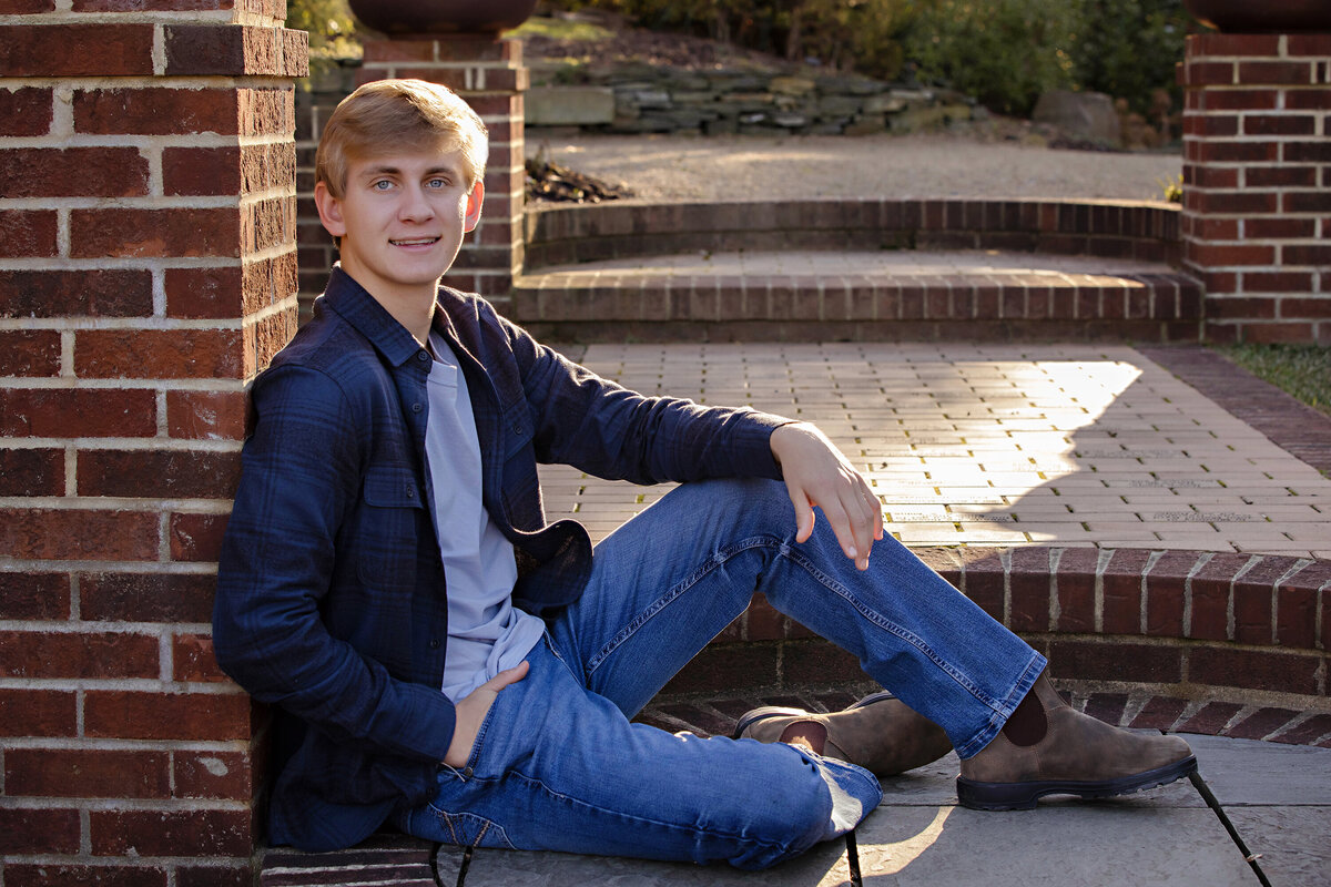 Relaxed fall portrait of young man in patterned shirt on brick steps at UNCC Botanical Garden