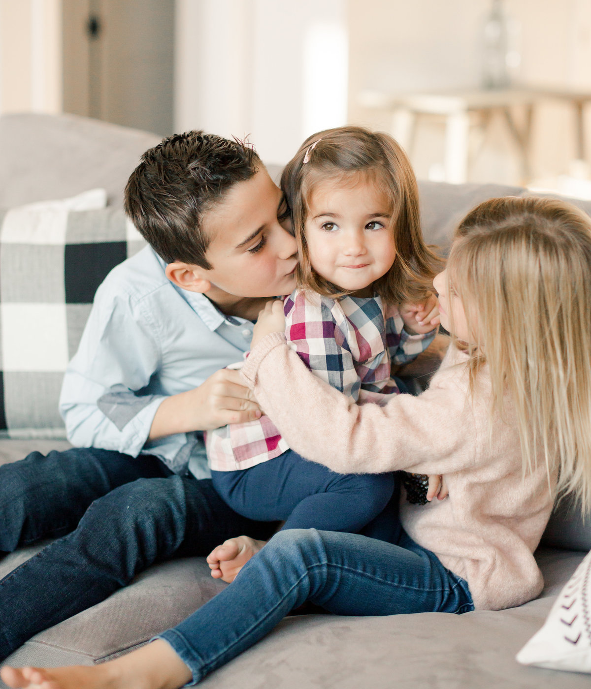 very sweet siblings of young sister cuddle on couch for lifestyle family photography