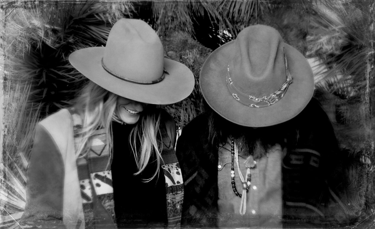 Musical duo portrait Amanda And Chris wearing cowboy hats hiding faces black and white