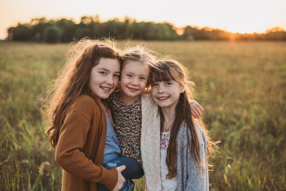 three girls at sunset in field