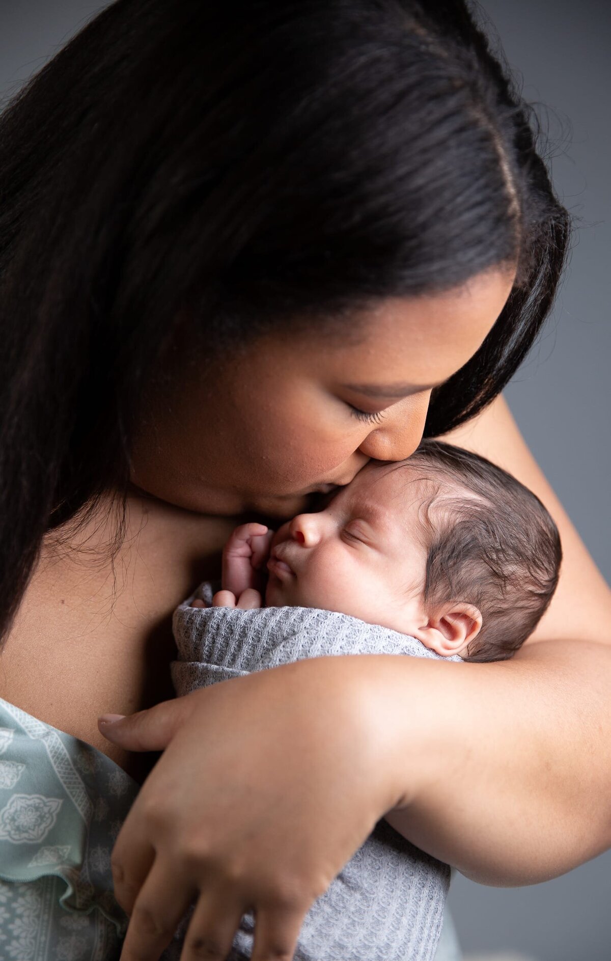 Mother kissing her newborn son. Portrait Photographer in Wake Forest.