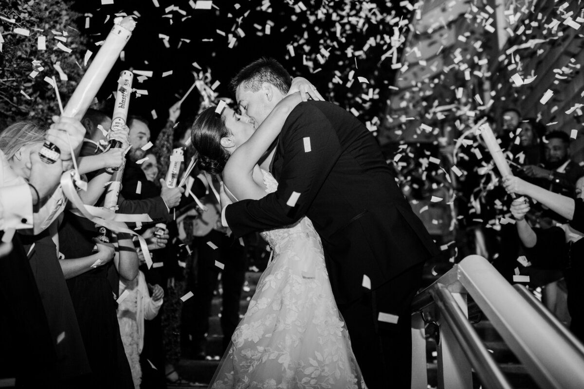 bride and groom kissing in the middle of confetti