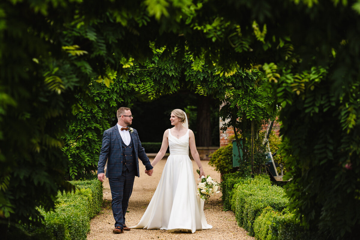 bride and groom walking through the grounds at stapleford park hotel
