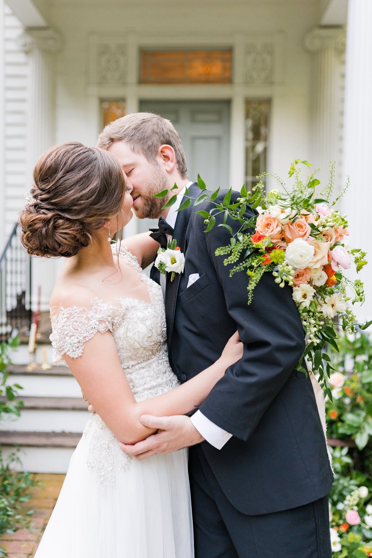 A newly married couple shares a kiss in front of the historic Holt House in Lexington, NC near Charlotte, NC.