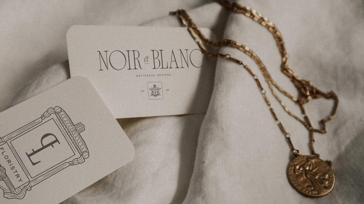 business cards and necklace on white sheet