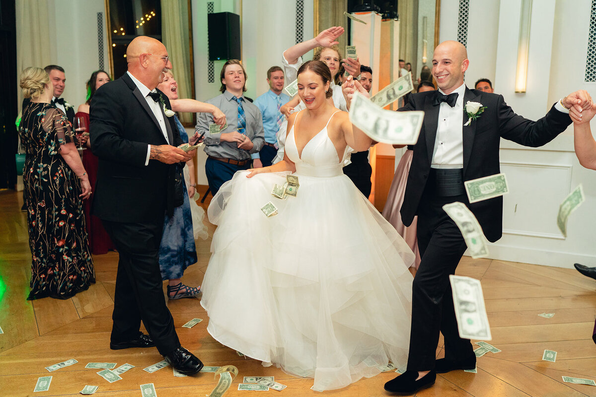 Greek wedding reception at the Dewberry Hotel in downtown Charleston. Bride and groom dance in circle with money flying through the air. Charleston based wedding photographer.