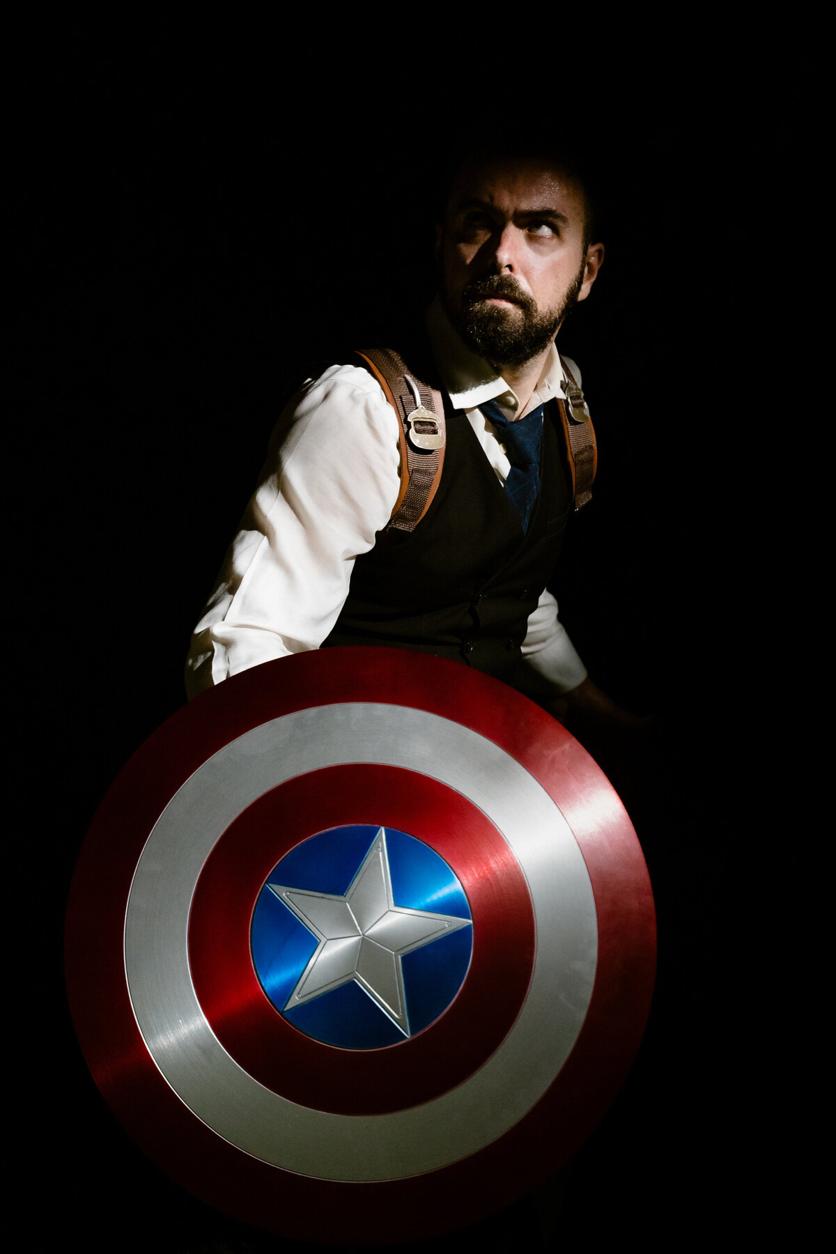 A person in a cosplay outfit of Captain America holding a shield.