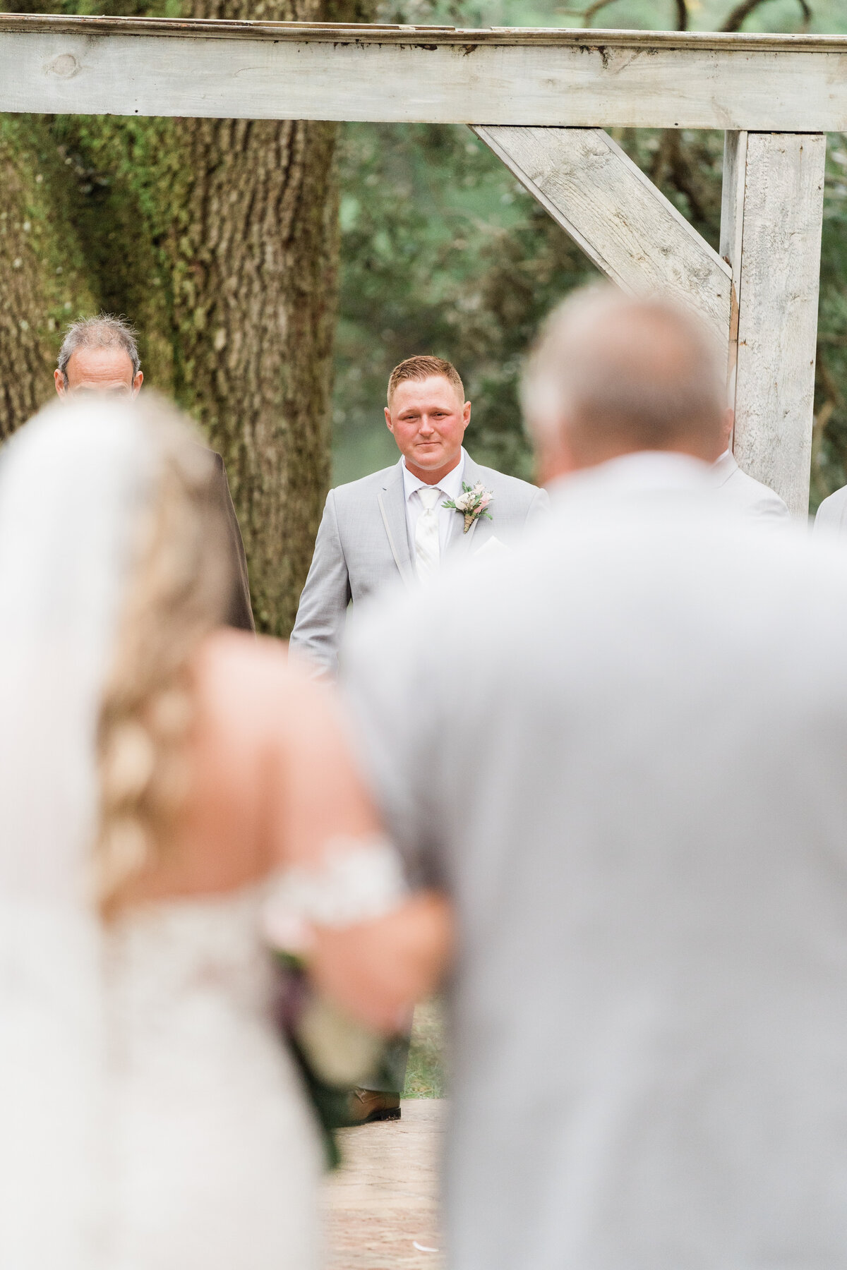 Photo of groom as bride walks down aisle