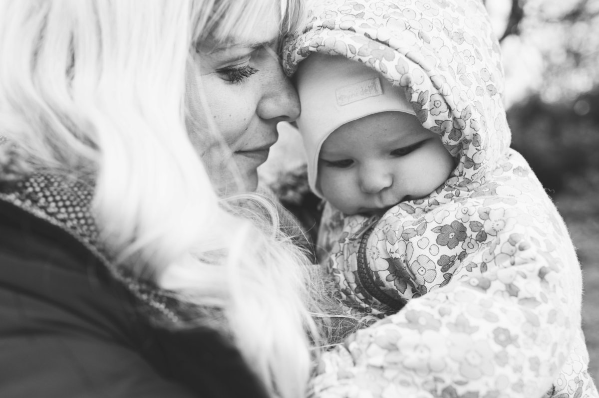 A black and white image of a mother and baby  in the park on a winter's day