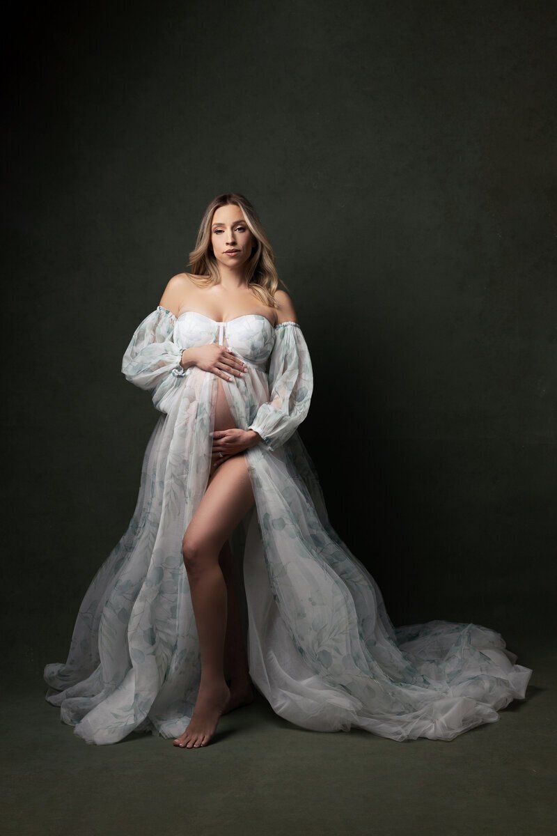 Pregnant mom wearing tulle dress holding bump, taken by maternity photographer nj
