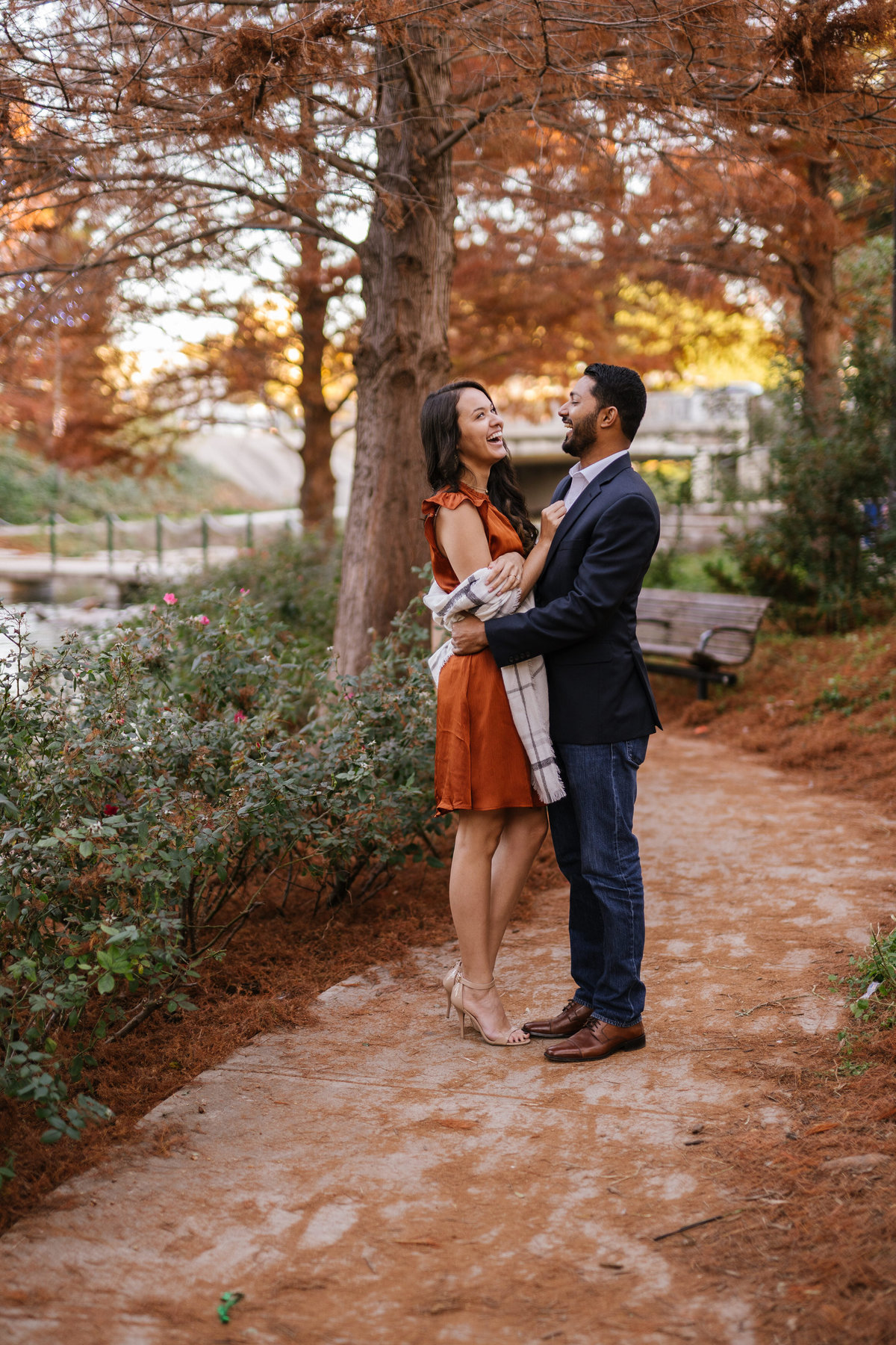 Beautiful fall engagement session for couple with leaves on the ground and standing next to a river.