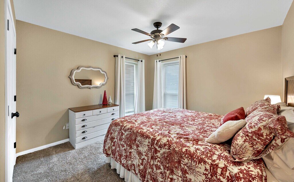 Bedroom with beautiful bedding and dresser in this four-bedroom, four-bathroom vacation rental home and guest house with free WiFi, fully equipped kitchen, firepit and room for 10 in Waco, TX.