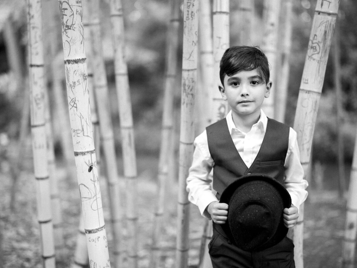 A small boy holding a fedora in front of him.