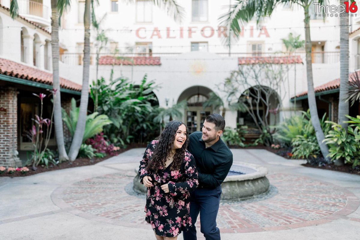 Engaged couple gets playful in the Villa Del Sol courtyard