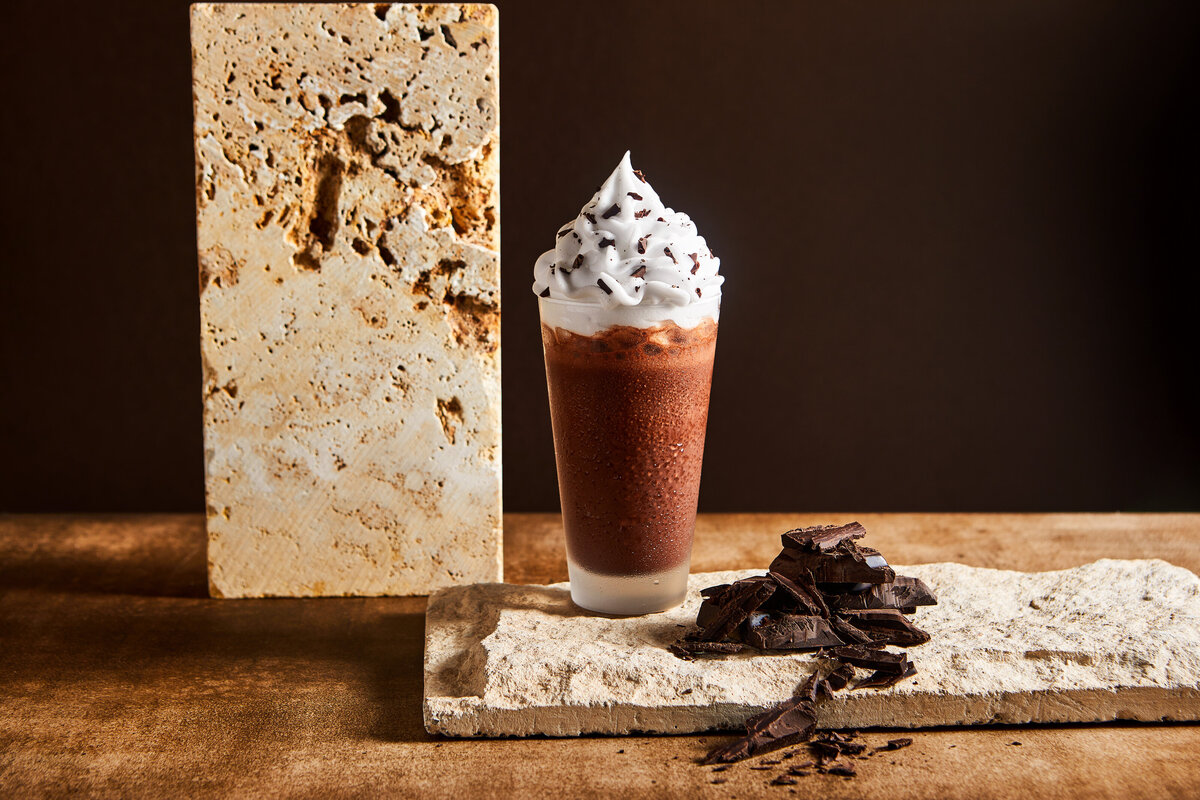 A frozen chocolate drink with chocolate shavings next to it.