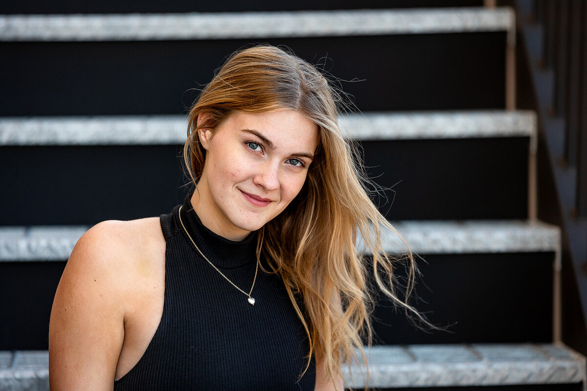 Senior girl wearing a black top smiles for the camera during her session.