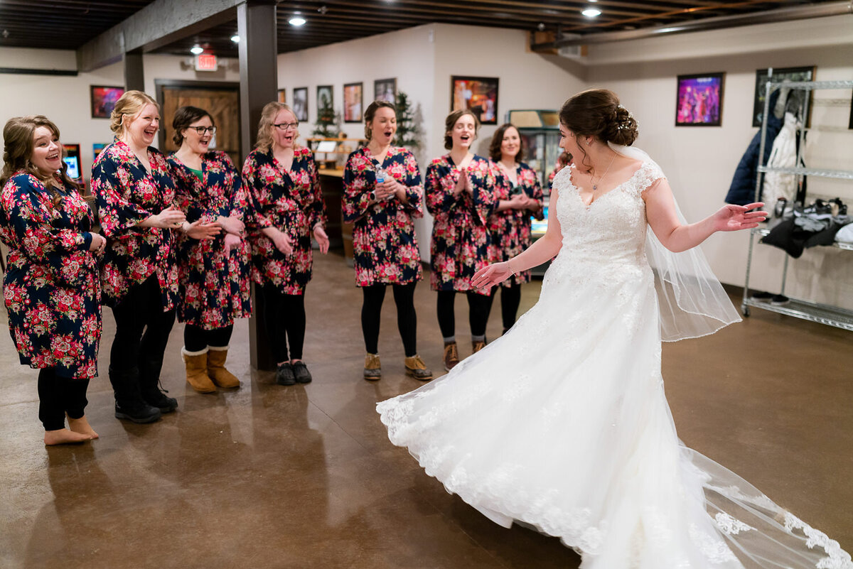 Bride shows off her dress to wedding party.