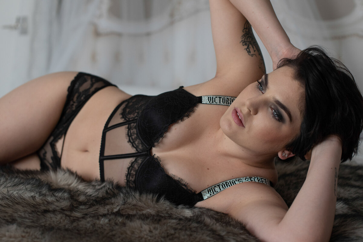 Woman on her side in bed wearing a black Victoria's Secret lingerie posing for Orlando Boudoir photographer Khim Higgins.