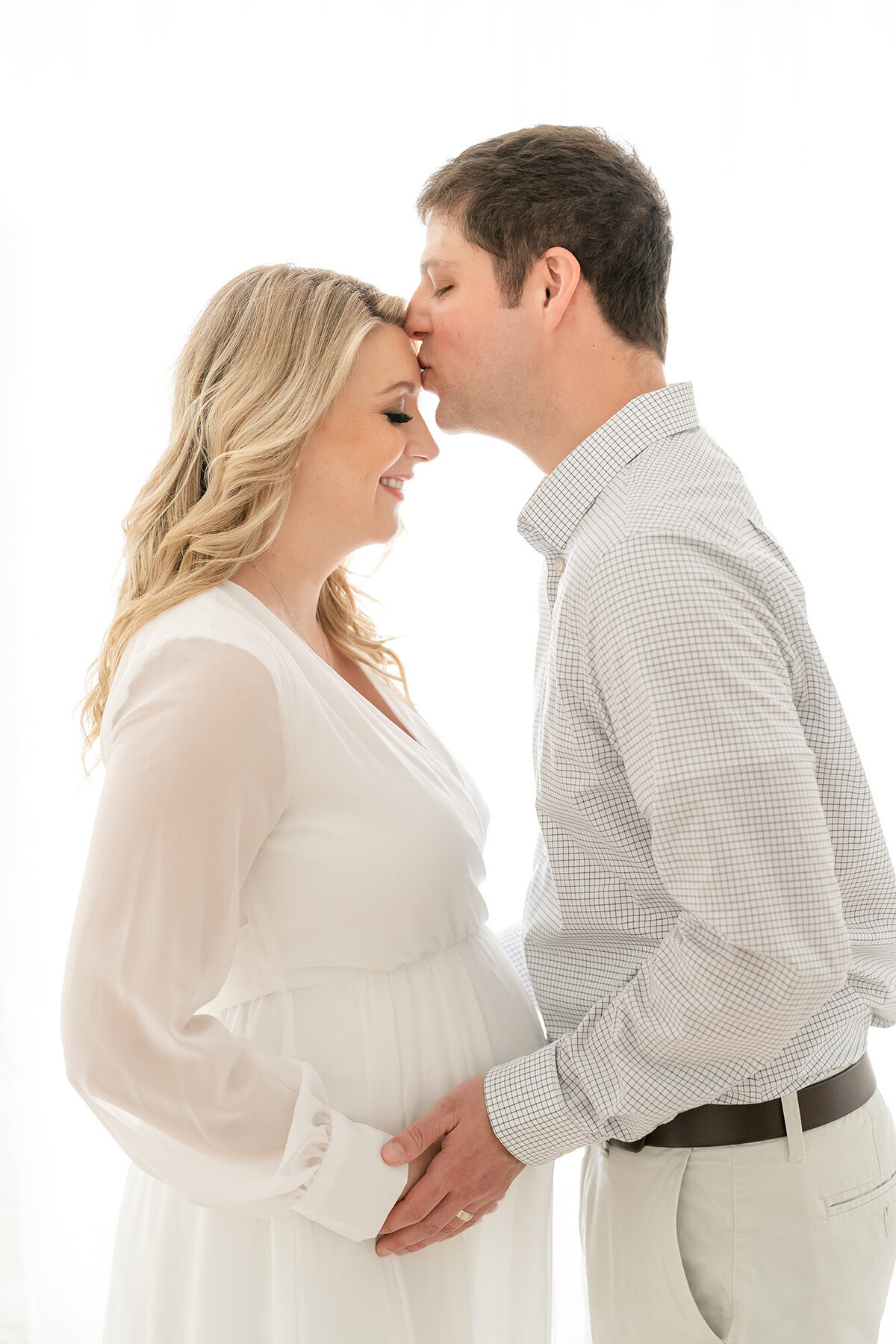 Husband kisses wife's forehead during pregnancy photo shoot at Julie Brock Photography in Louisville Ky