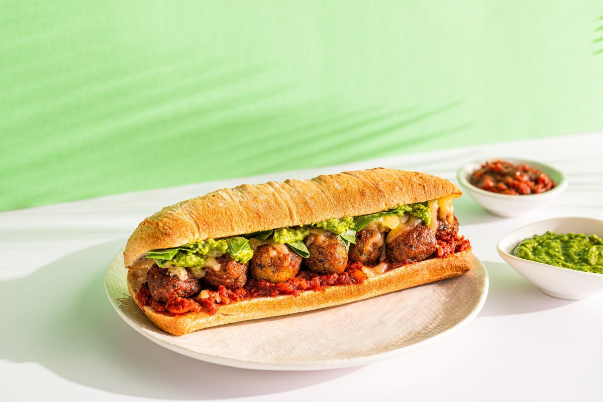 A plate with a large meatball sub on it.