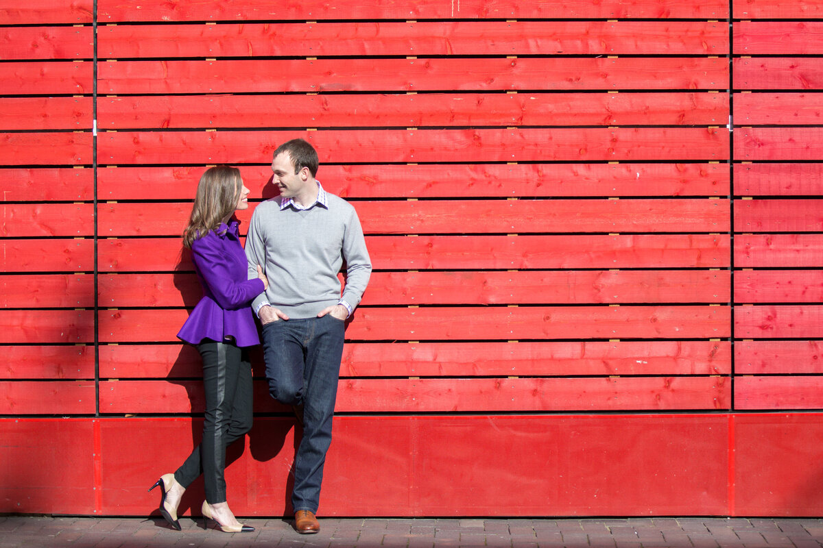 Couple together in front of red wood wall