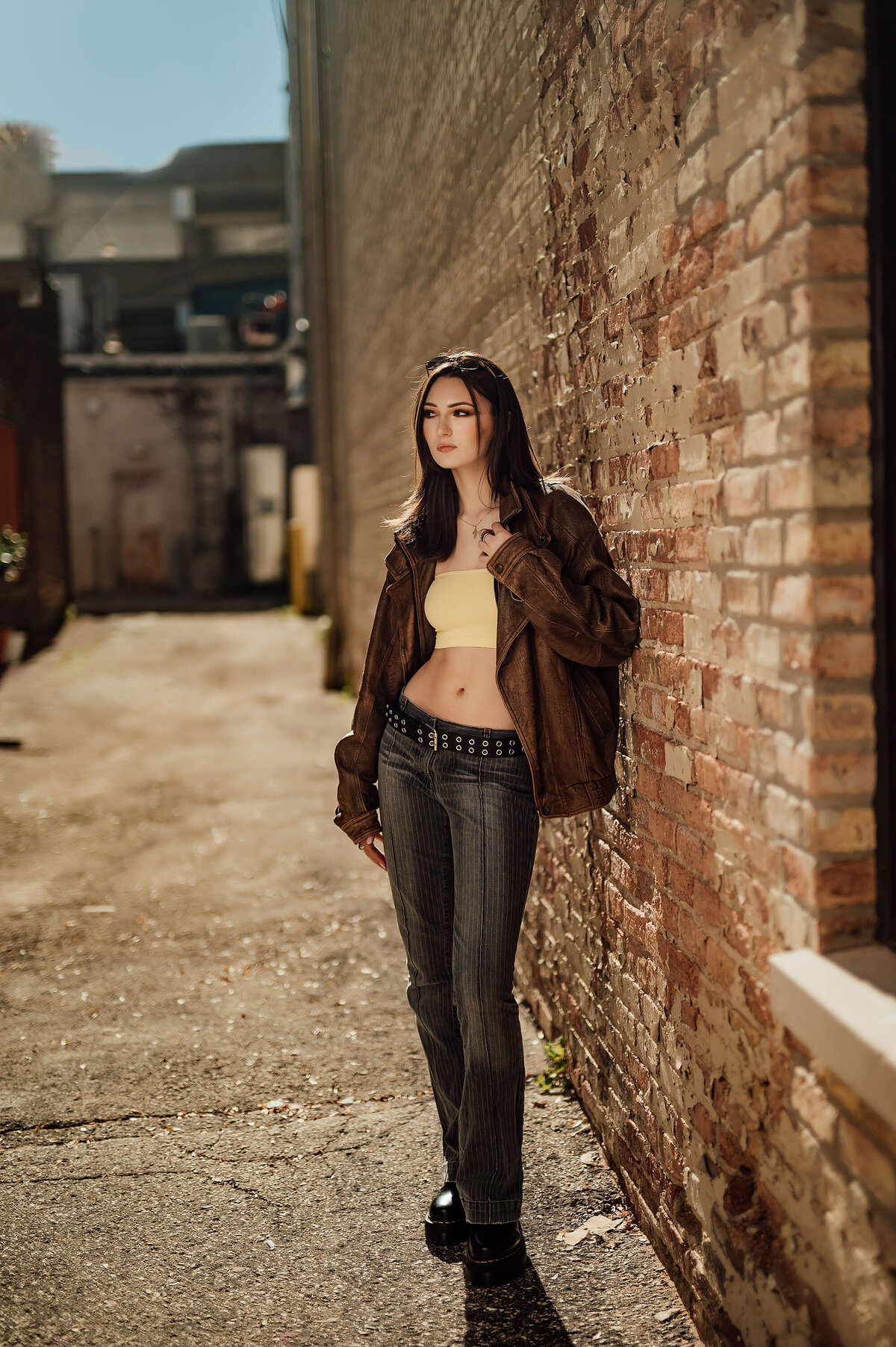 A senior from Brookfield Central High School poses in alternative attire along a weathered brick wall in Milwaukee's Third Ward.