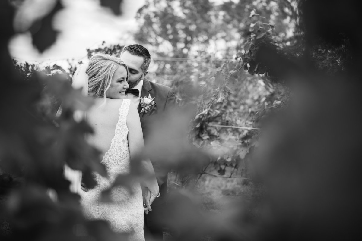 black and white wedding photo of bride and groom through the vines at The Vineyards at Aquebogue