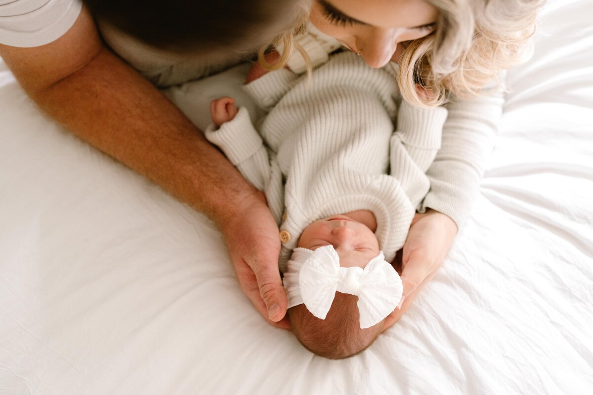 Couple embracing newborn from above on the bed