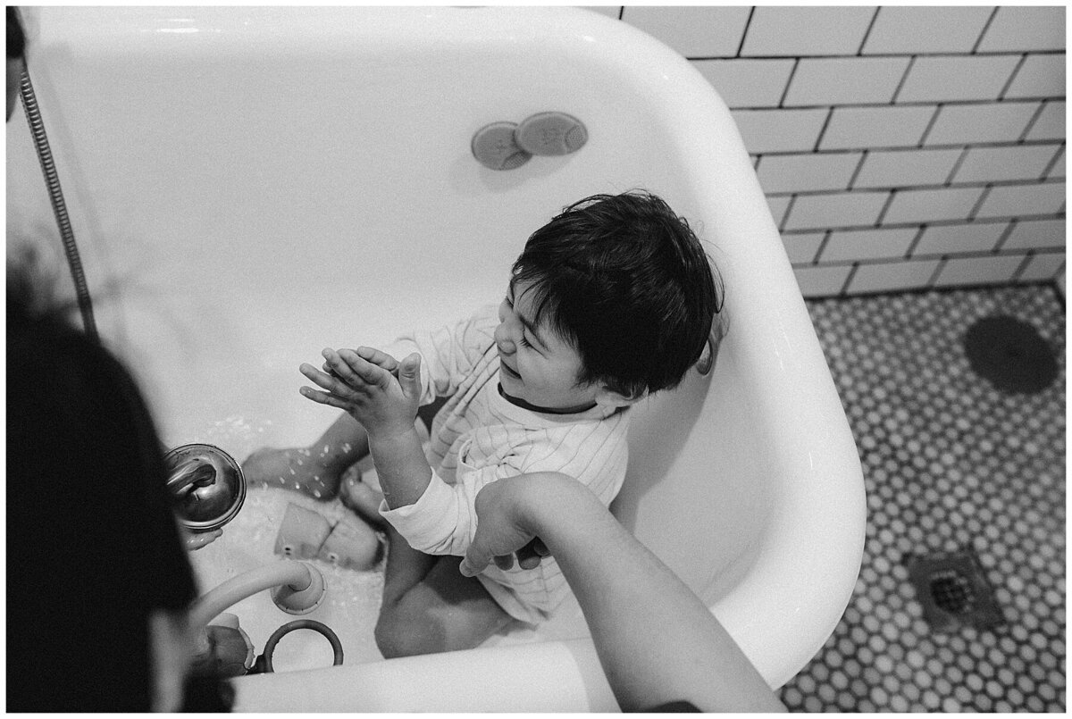 Child sitting in a bathtub as mother fills it with water at family session at home in Austin Texas