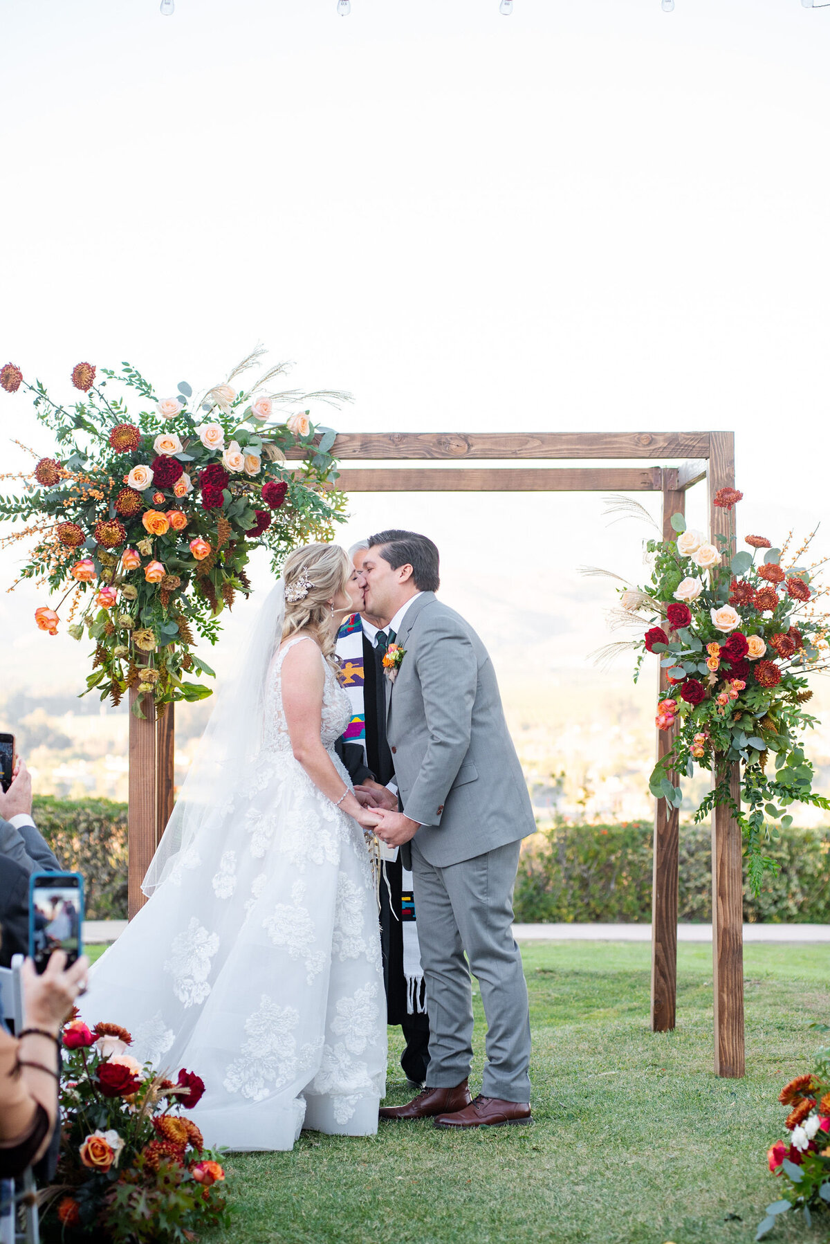 A bright and colorful wedding arbor full of bright, fresh floral bouquets/