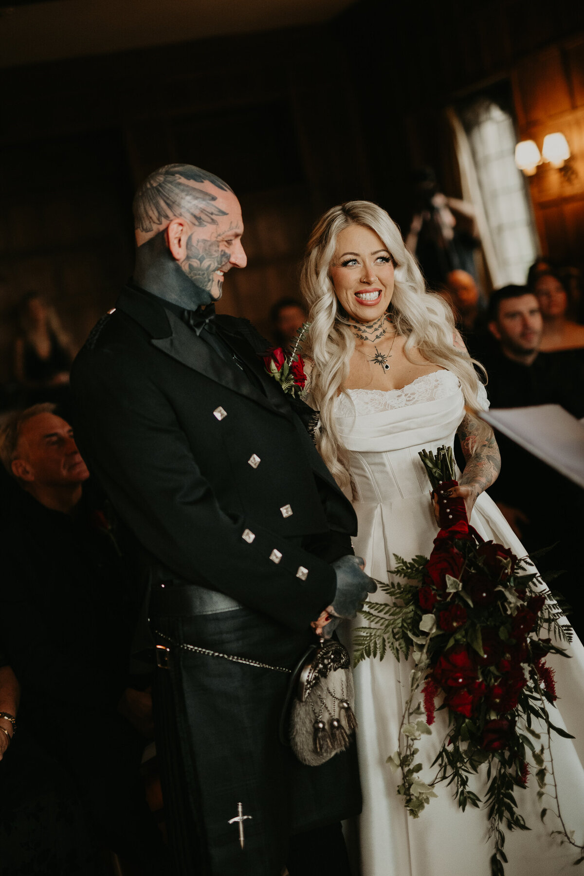 Tattooed Bride and Groom smile during their wedding ceremony at Lympne Castle in Kent.