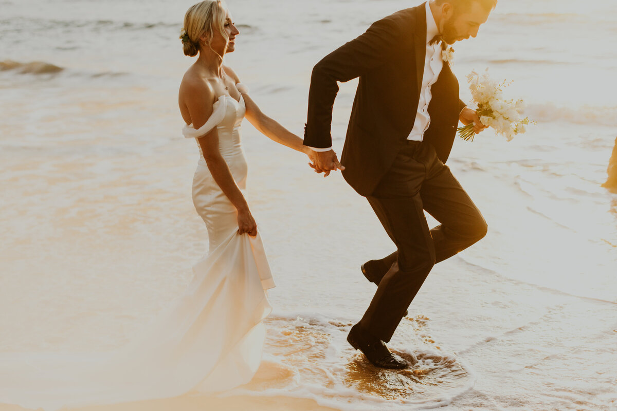 bride and groom running through ocean