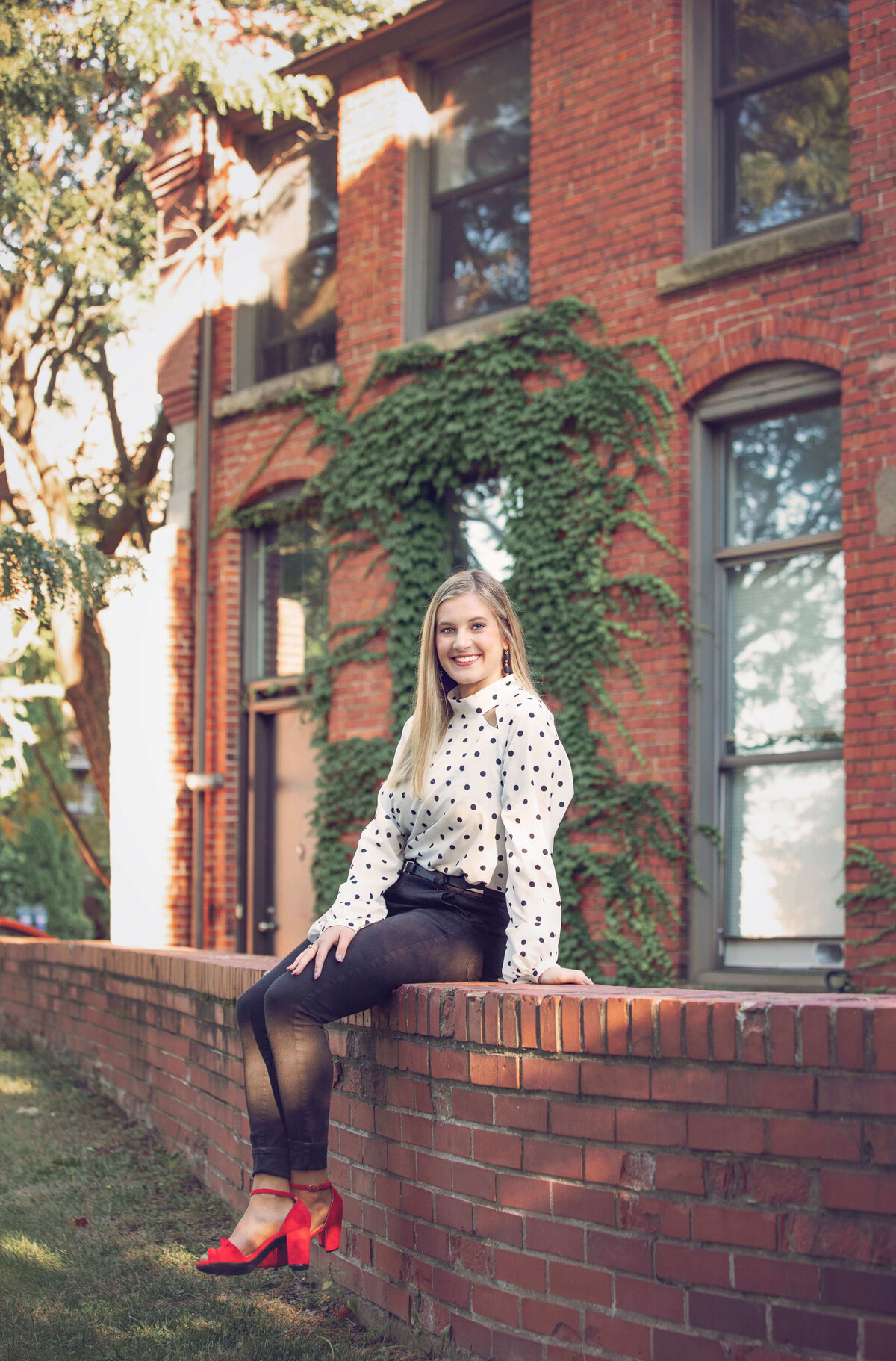 Senior photo of a  girl sitting on a brick  wall  in downtown Erie Pa