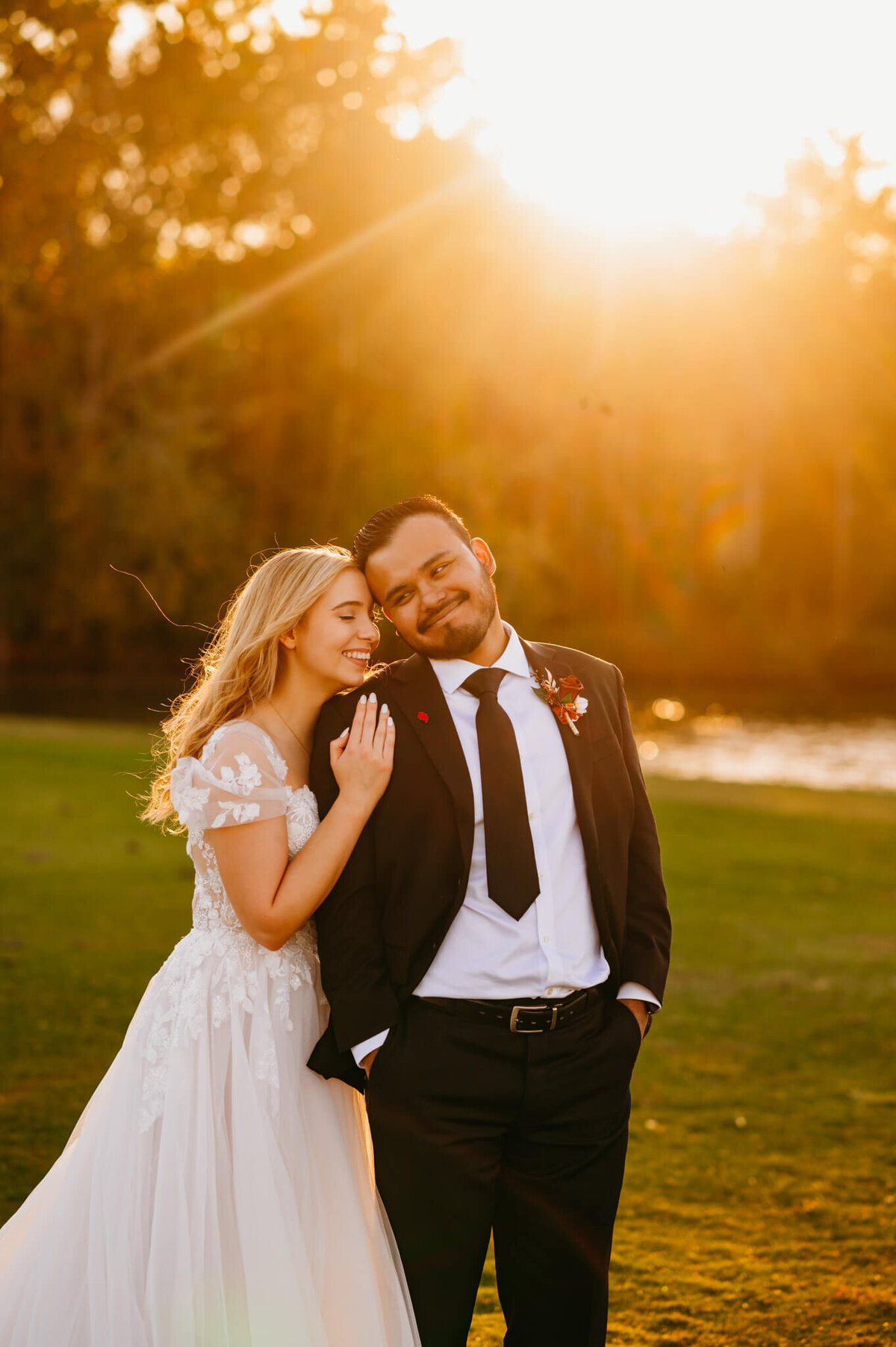 photo of a bride cuddling the groom's back while he laughs at sunset