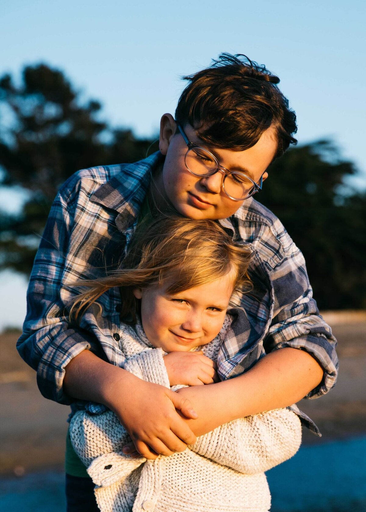 teenage boy hugging young sister at crown memorial beach in alameda.