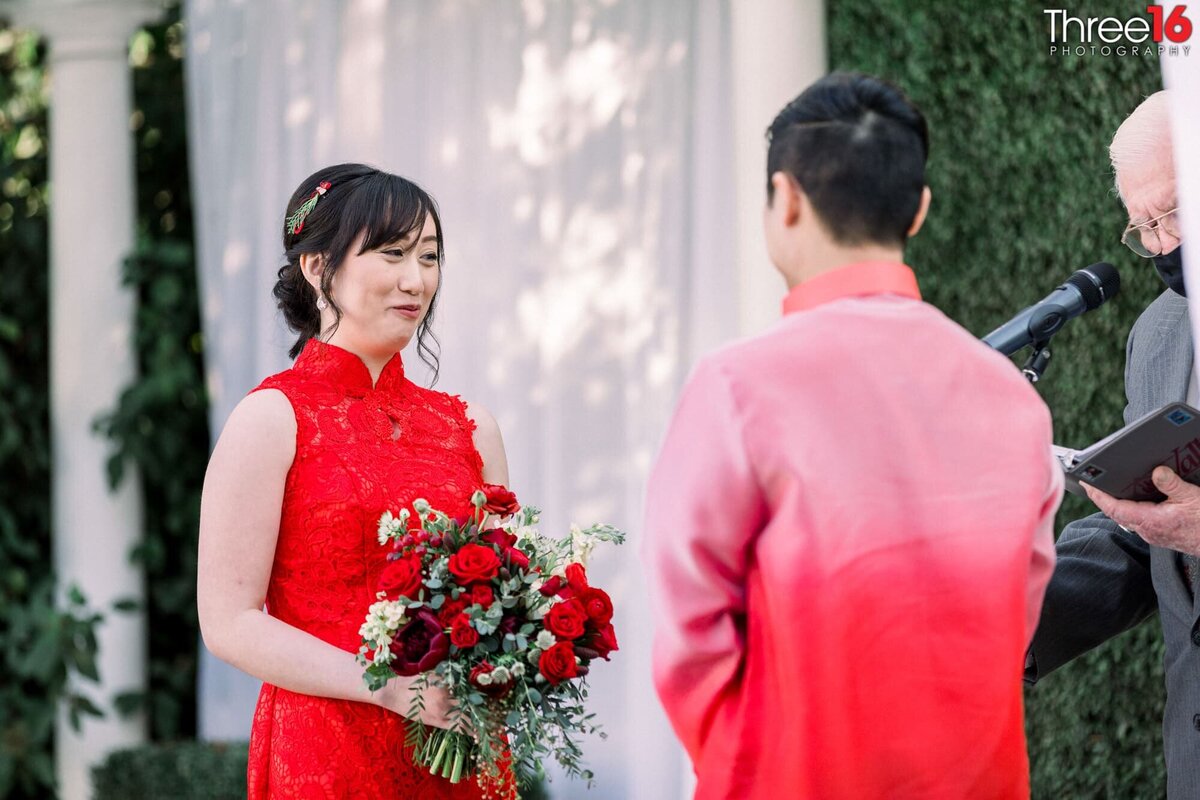 Bride and Groom wearing red stare at each other at the altar