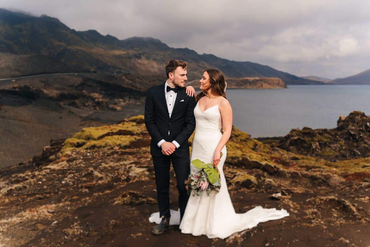 This couple shares a beautiful moment, looking into each other's eyes, with the stunning Icelandic coast as their backdrop—where love and nature blend in perfect harmony.