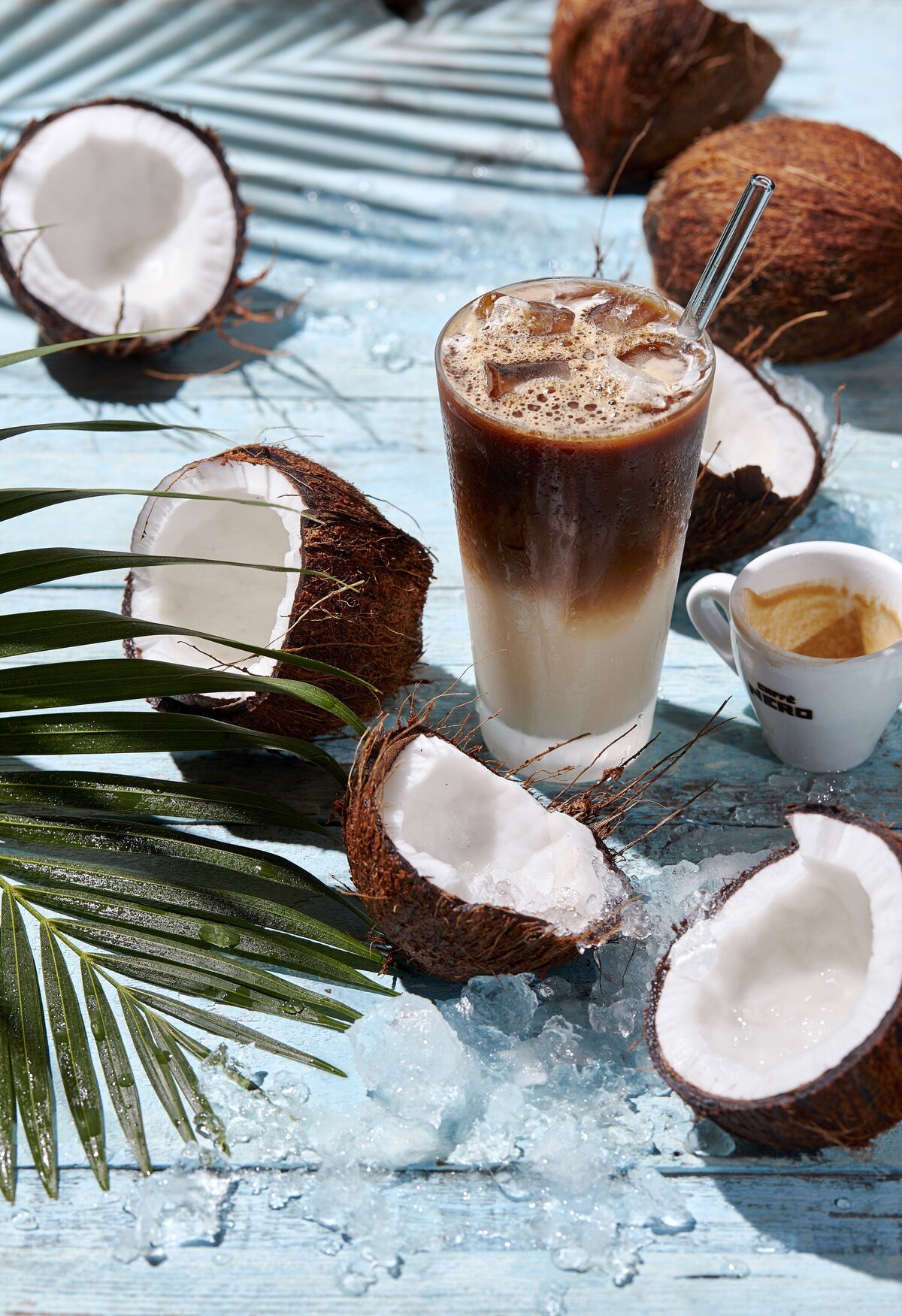A coconut latte with halved coconuts around it.