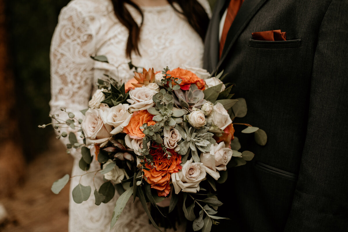 bride and groom holding a rust orange southwest themed bouquet