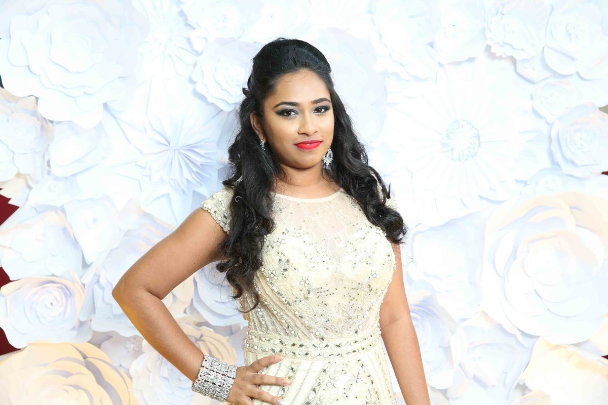 A young lady poses in front of a 3d, monochrome white, floral photobooth backdrop. Photobooth by Ross Photography, Trinidad, W.I..