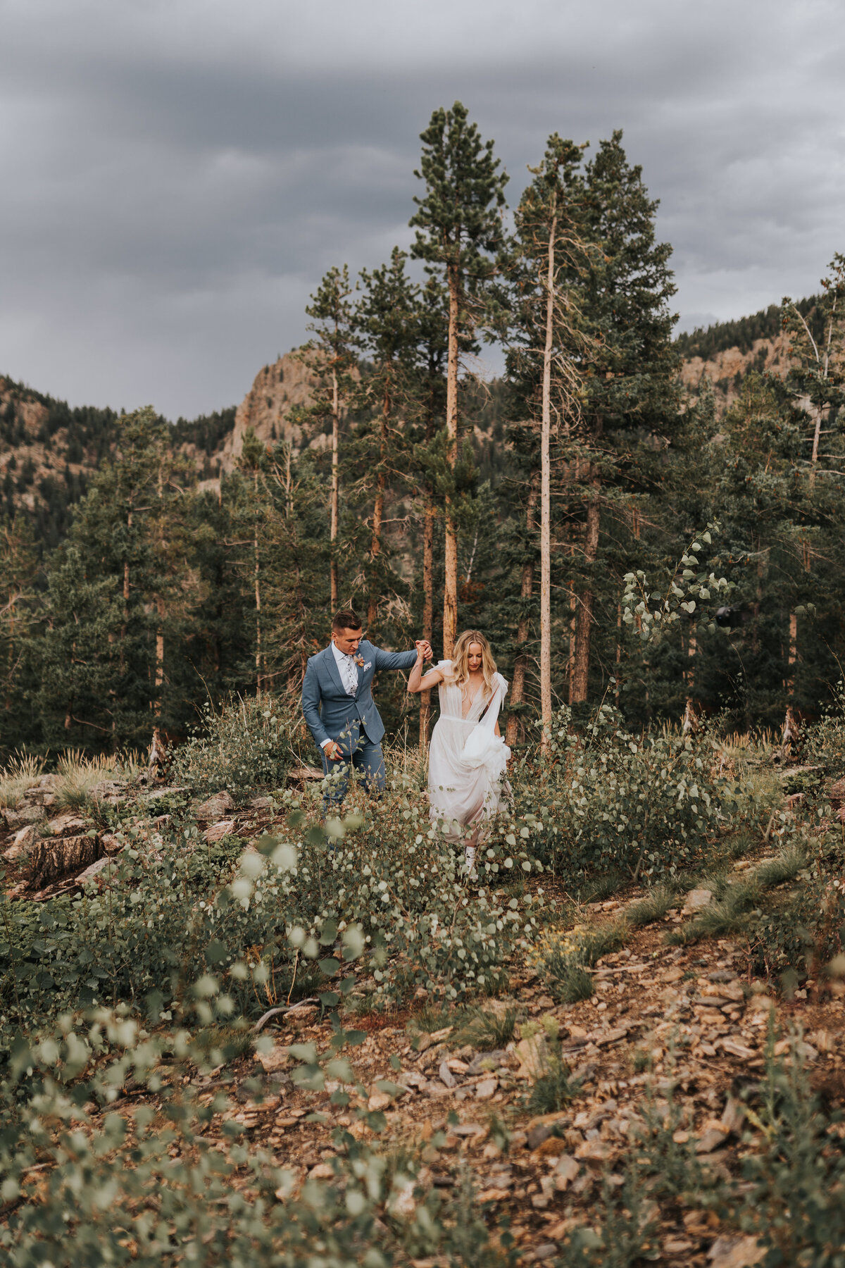 Bride and groom walking in a valley with a mountain range background