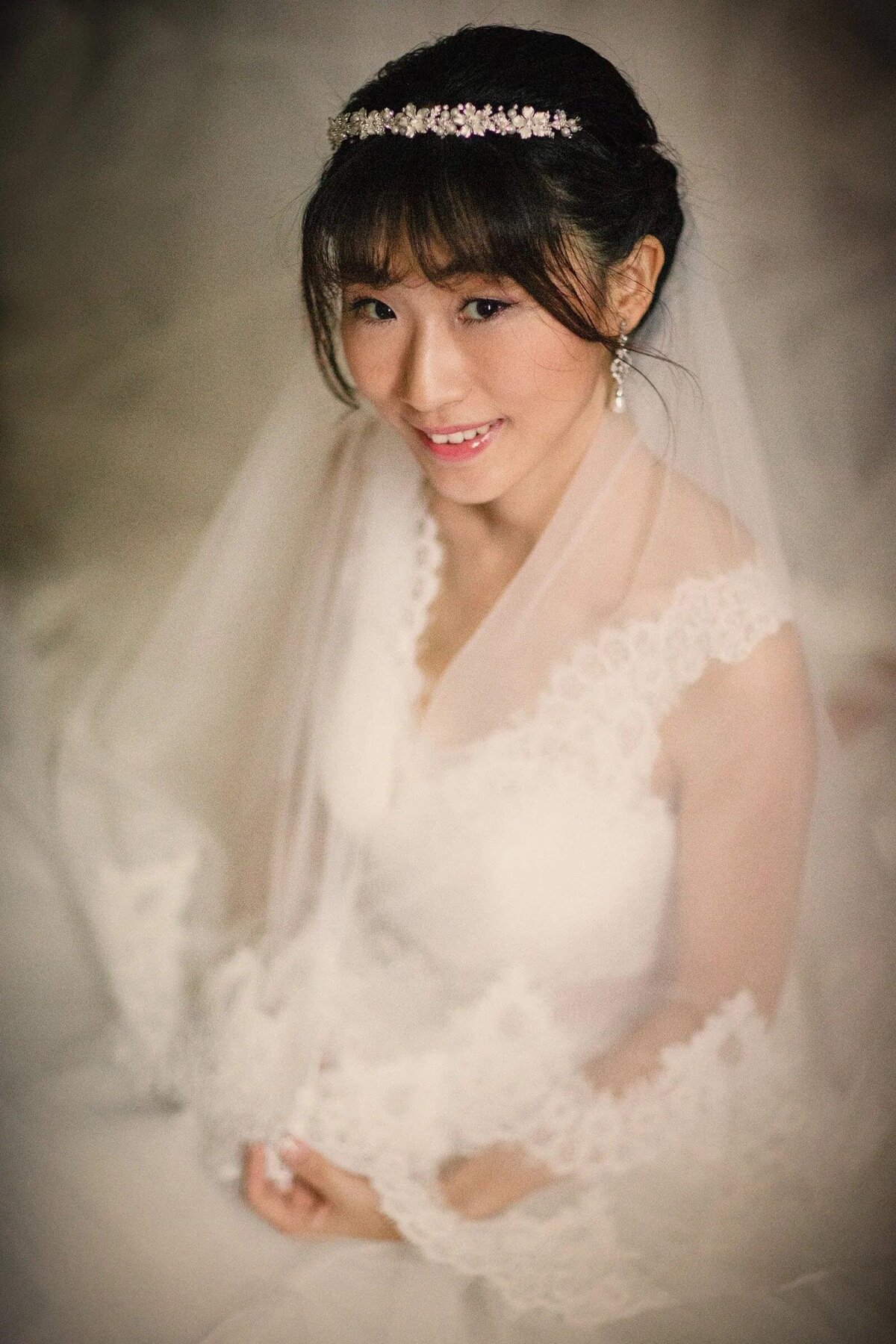A bride sitting down smiling with her hands in her lap