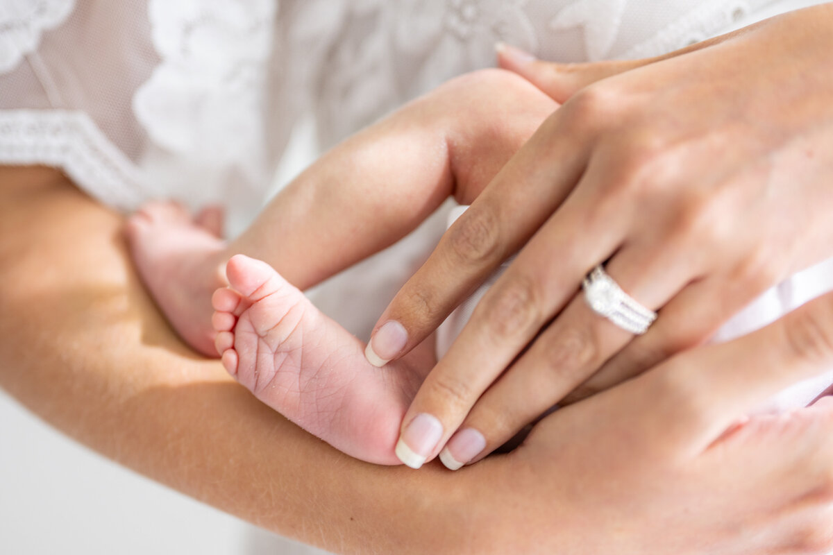 A close up photo from a newborn session of a mother's arms cradling her baby