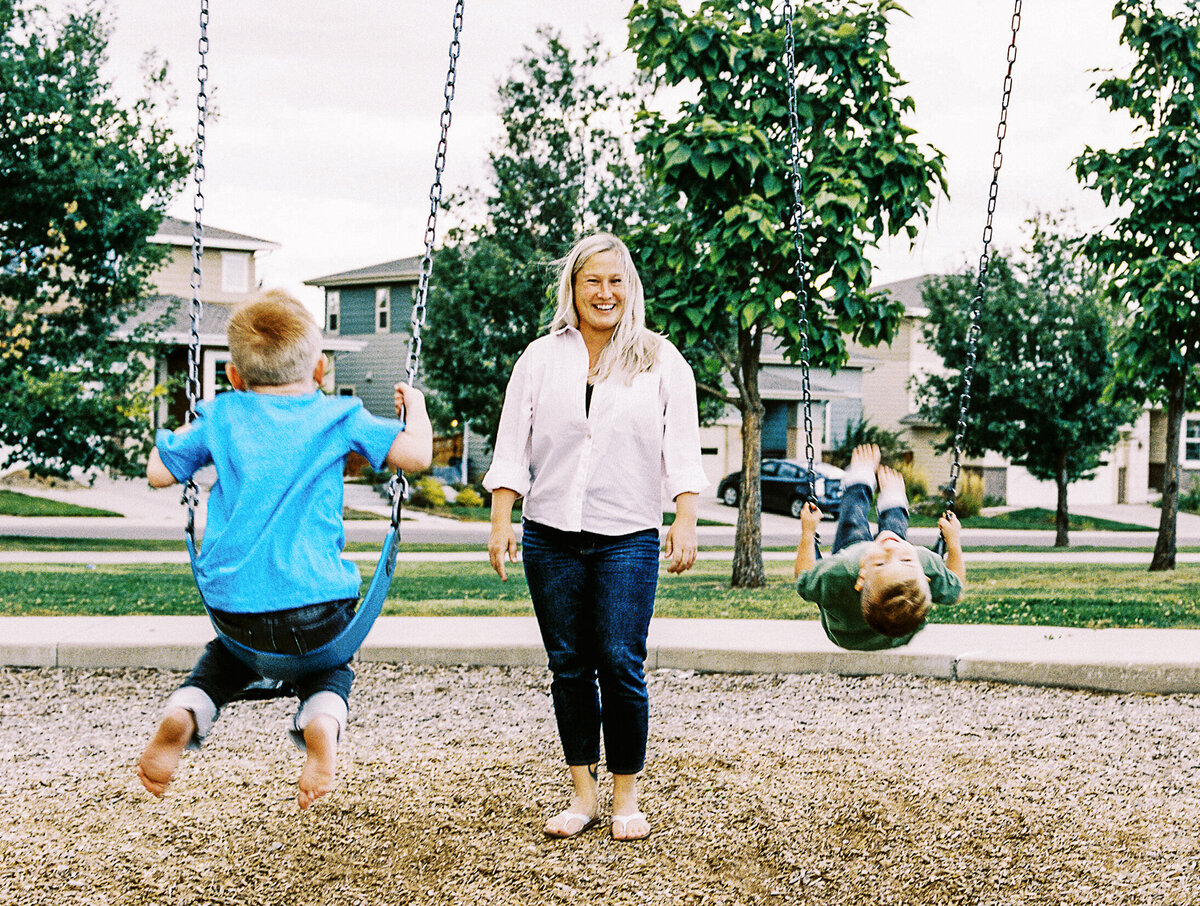 a mom pushes her boys on swings