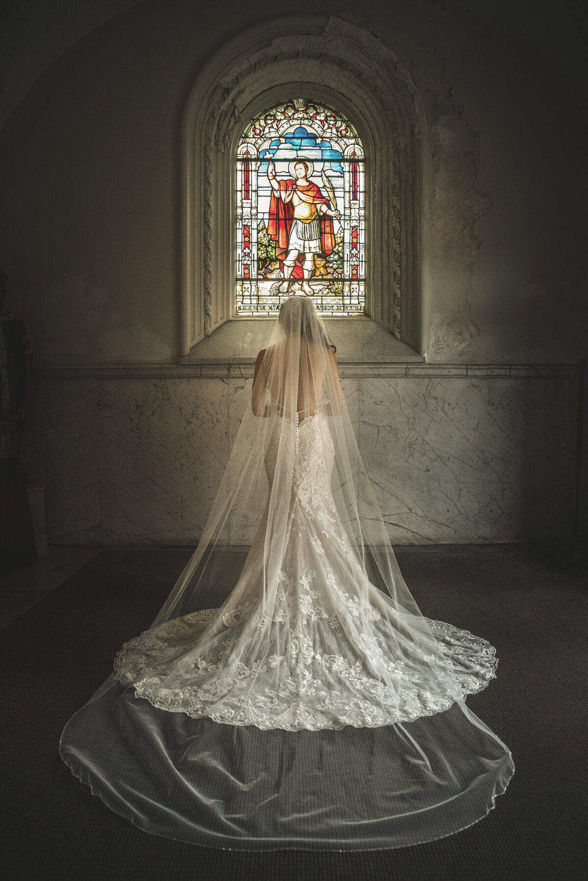 Bride showing off dress in front of stained glass window at Saint Patrick Church.