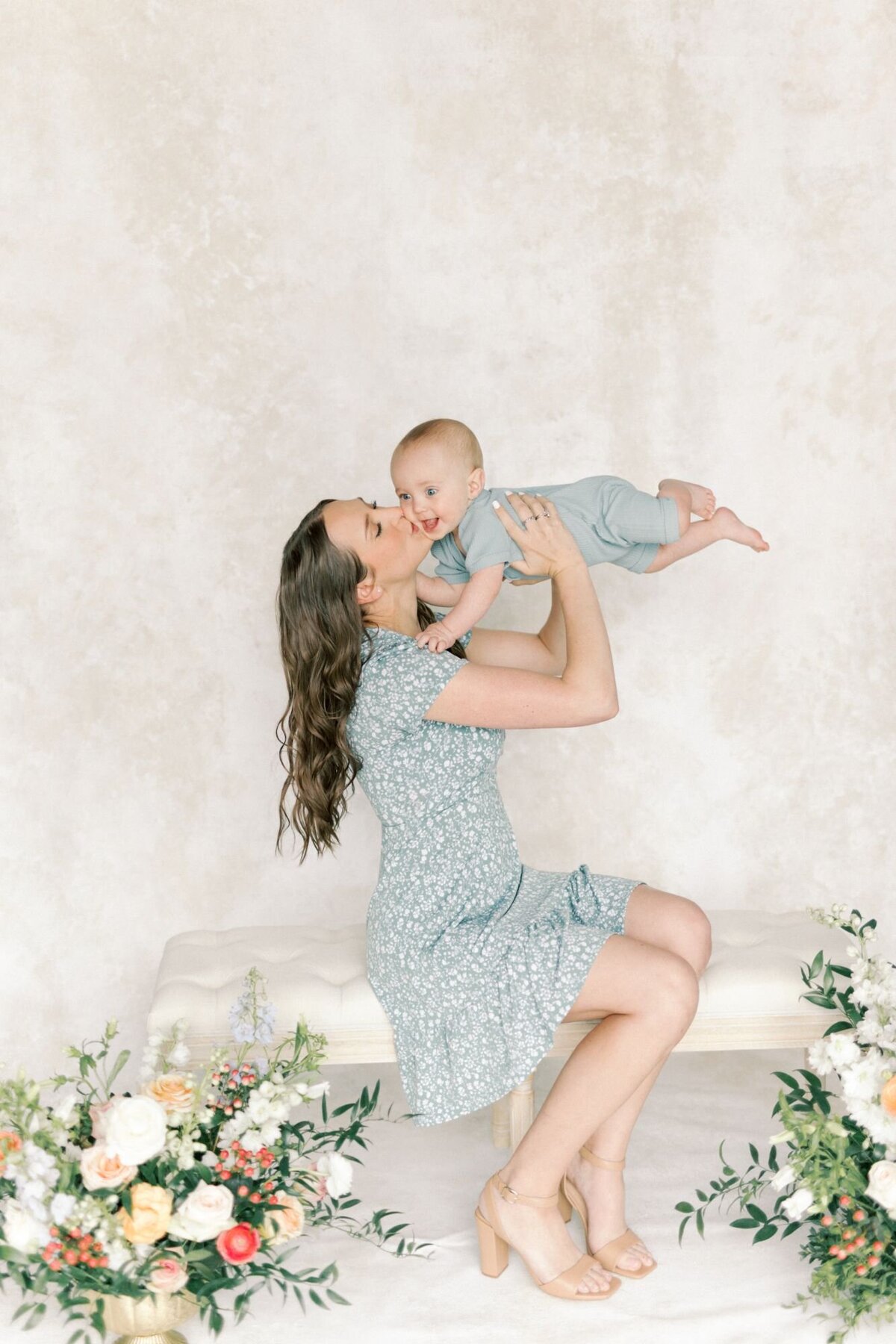 Woman holds her baby up in the are to kiss the baby.