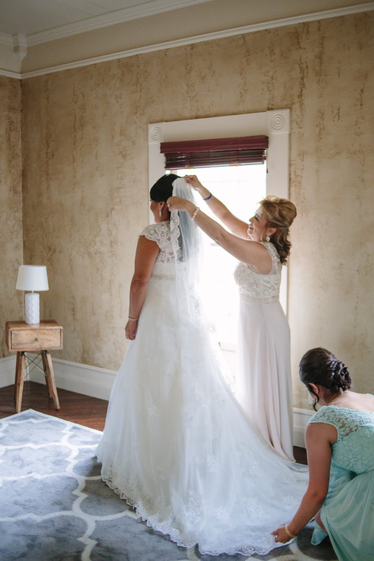 Mother of bride puts veil on her daughter just before getting ready for Texas Hill Country wedding ceremony.