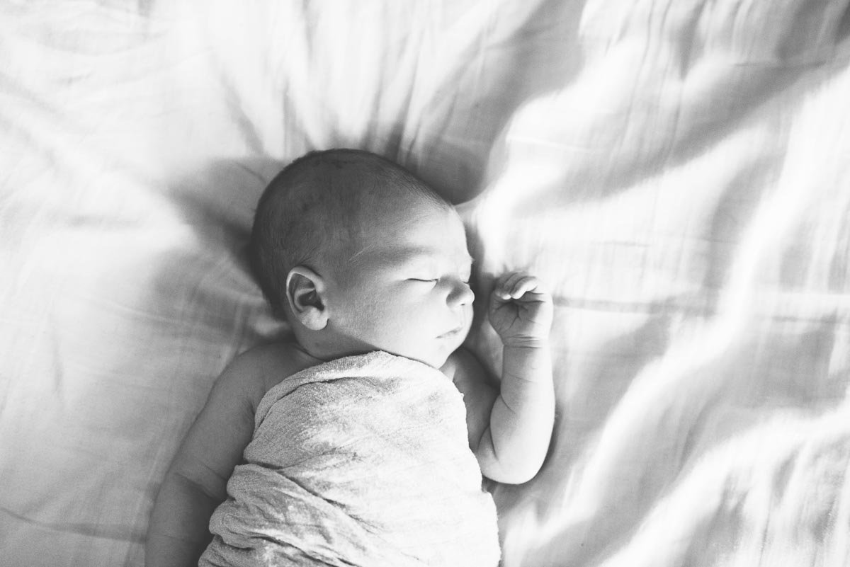 baby sleeping on white bed in black & white portrait