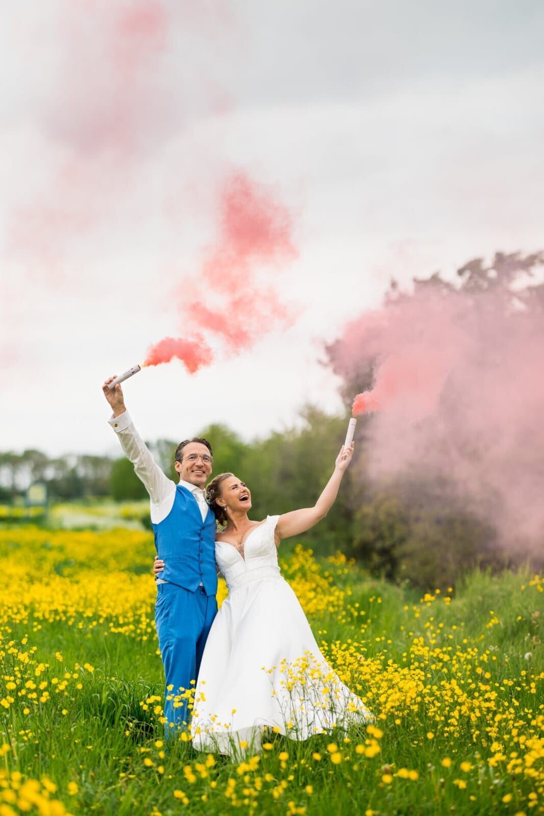 Bruidspaar straalt van blijdschap op grasveld omringd door gouden fakkels, perfect georganiseerd door weddingplanner en ceremoniemeester