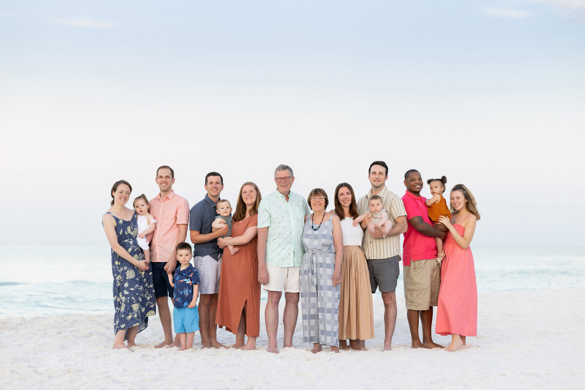 An extended family standing together smiling at the beach in Watercolor Florida at sunrise.